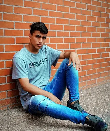 a teen sitting by a wall
