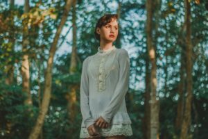 woman-in-white-long-sleeved-mini-dress-standing-under-trees