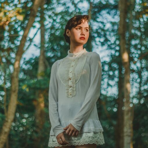 woman-in-white-long-sleeved-mini-dress-standing-under-trees