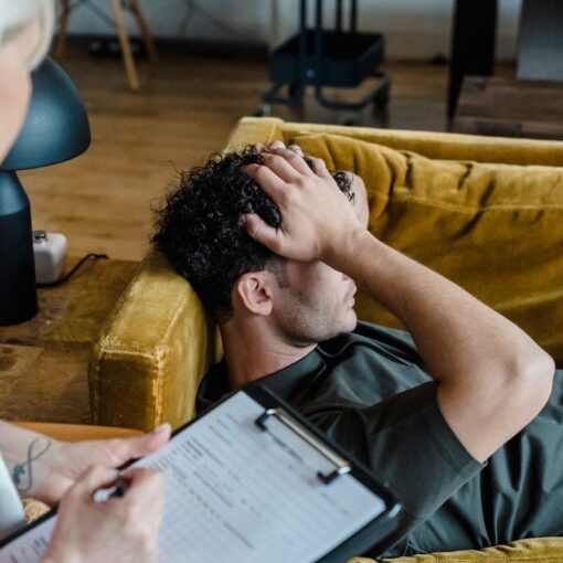 a-man-lying-on-the-sofa-while-holding-his-head