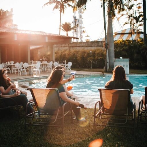 people-sitting-on-sunloungers-near-swimming-pool