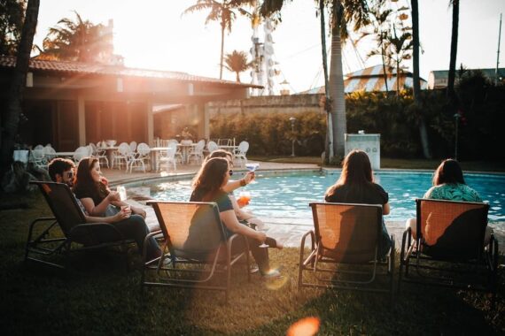 people-sitting-on-sunloungers-near-swimming-pool