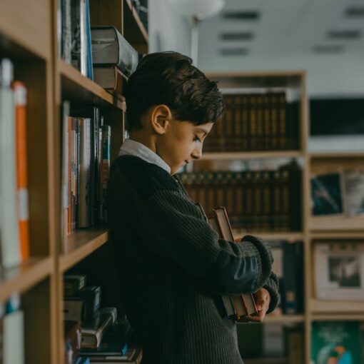 boy-hugging-books-while-leaning-on-a-bookcase