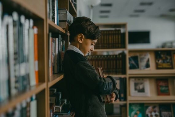 boy-hugging-books-while-leaning-on-a-bookcase