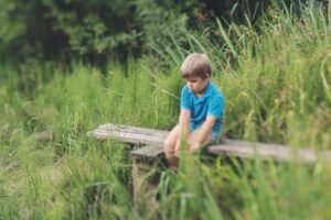 boy-in-blue-polo-t-shirt-sitting-on-brown-wooden-bench