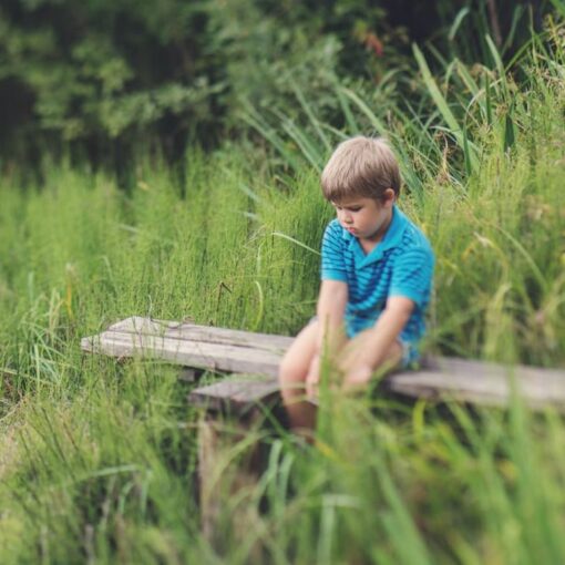 boy-in-blue-polo-t-shirt-sitting-on-brown-wooden-bench